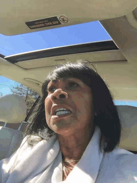 a woman sitting in a car with an air bag warning on the sunroof