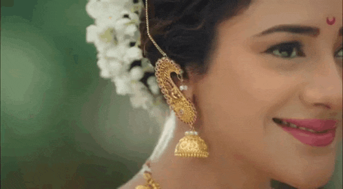 a close up of a woman 's face with a flower in her hair and earrings .