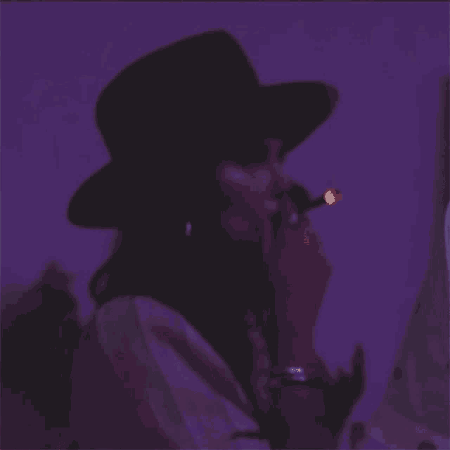 a woman wearing a hat is smoking a cigarette in a dark room