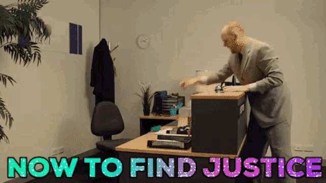 a man standing in front of a desk with the words now to find justice