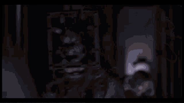 a zombie with a cage around his head is looking at the camera with his mouth open .