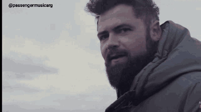 a man with a beard is wearing a green jacket and the words passengermusicarg are above him