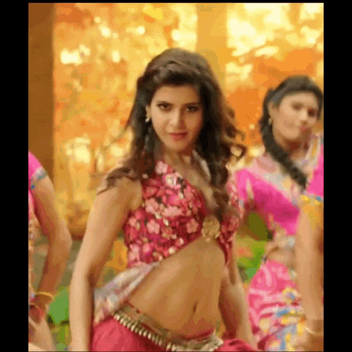 a woman in a floral top is dancing in front of a group of women .