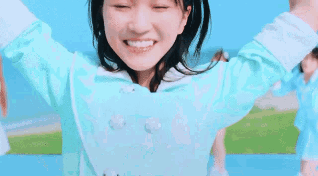 a girl in a blue shirt is smiling with her arms up