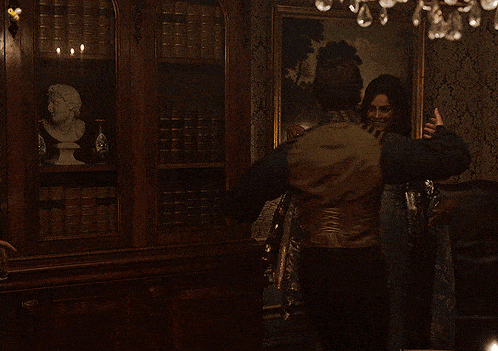 a man and a woman are hugging in front of a painting on the wall