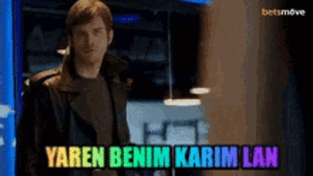 a man in a black leather jacket is standing in front of a sign that says yaren benim karim lan