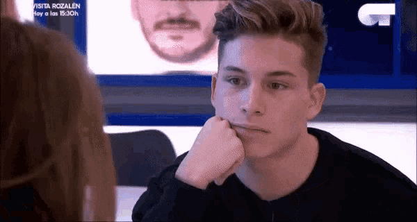 a young man with his hand on his chin looking at a woman .