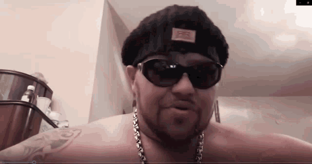 a man without a shirt is wearing sunglasses and a hat with the word fuel on it
