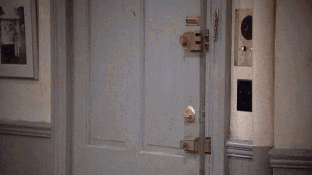 a man in a blue jacket is standing in a doorway with his arm outstretched ..