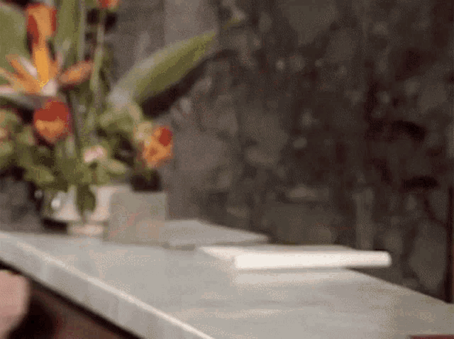 a vase of flowers sits on a counter in front of a wall
