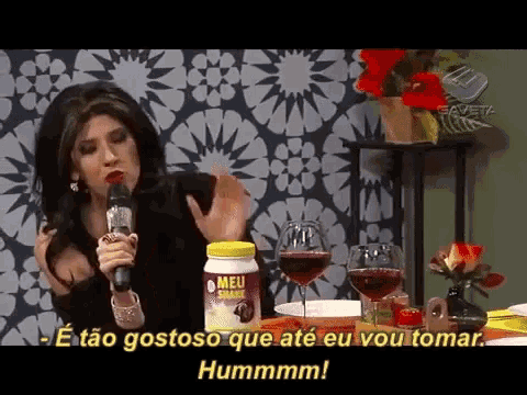 a woman singing into a microphone with a jar of meu shake in front of her