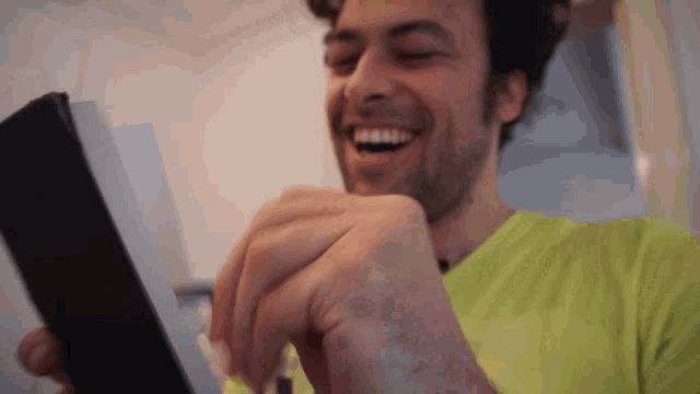 a man in a neon green shirt is smiling and holding a black object