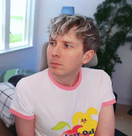 a man wearing a t-shirt that says lazy oaf sits in a chair