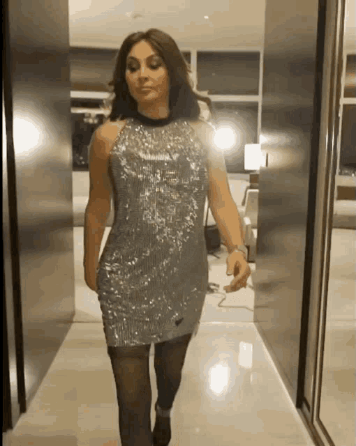 a woman in a sequined dress is walking down a hallway