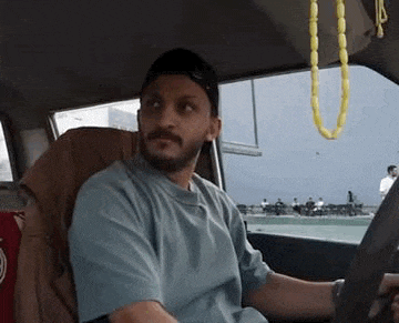a man is sitting in the driver 's seat of a car and looking at the camera .