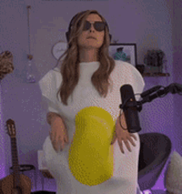 a woman is standing in front of a microphone wearing an egg costume