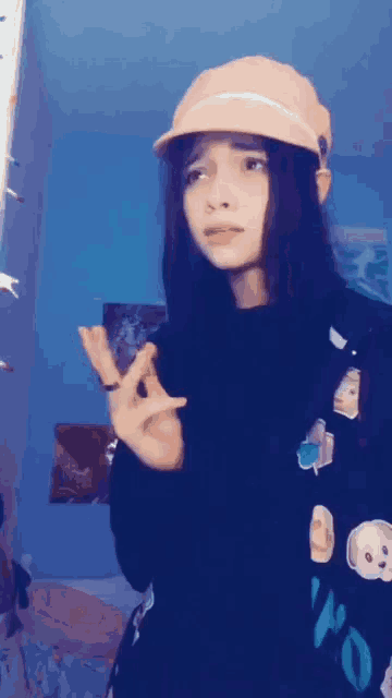 a girl wearing a pink hat and a black sweater is making a funny face