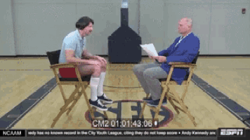 two men are sitting in chairs on a basketball court with ncaam written on the bottom of the screen