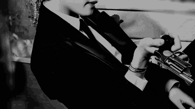 a man in a suit and tie is holding a revolver