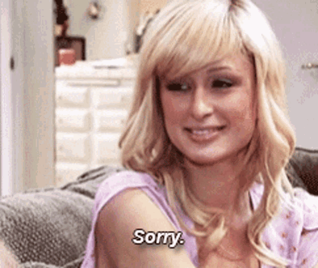 a blonde woman is sitting on a couch and saying sorry