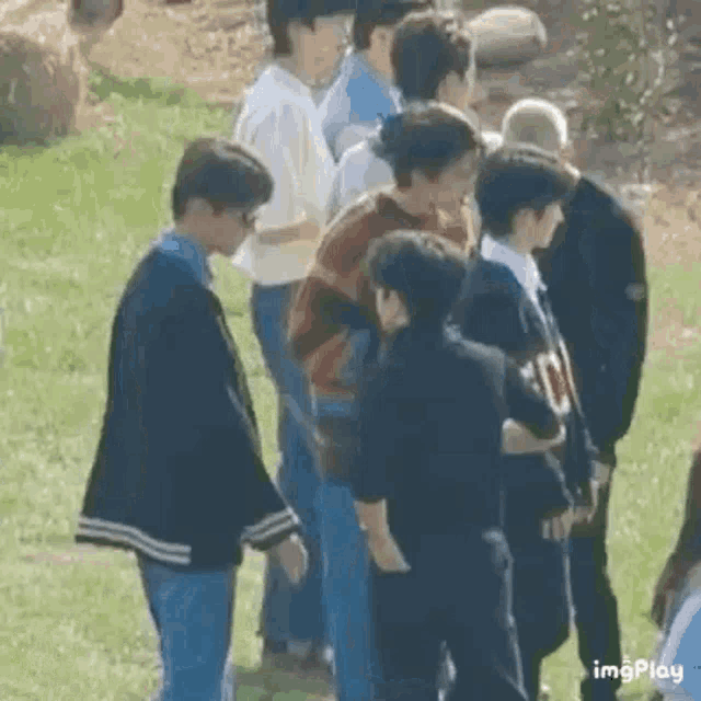 a group of young men are standing in a line on a grassy field .