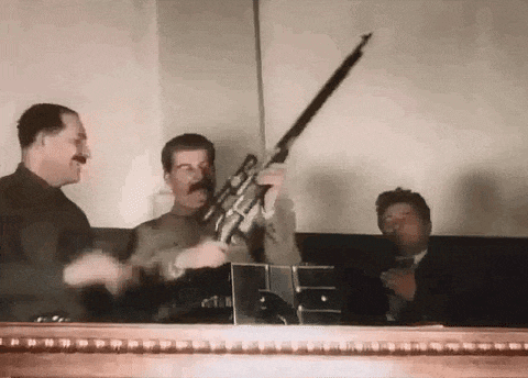 a man is holding a gun in a room with other men