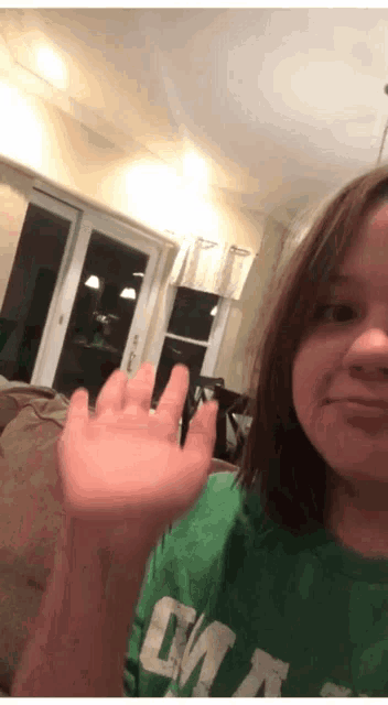 a girl wearing a green shirt with the word canada on it waves her hand