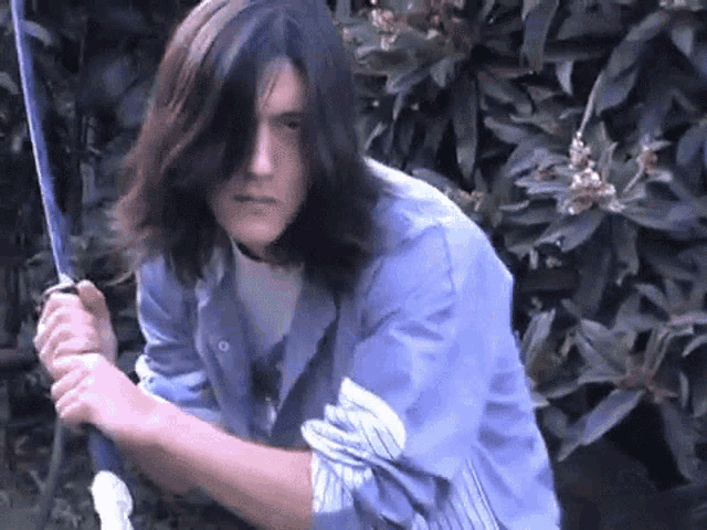 a young man with long hair is holding a broom in his hands