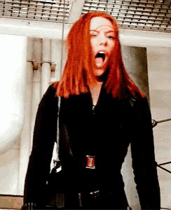 a woman with red hair is wearing a black jacket with the letter i on the buckle