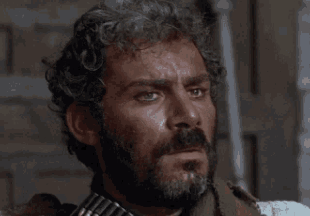 a man with a beard is holding a gun in his hand .