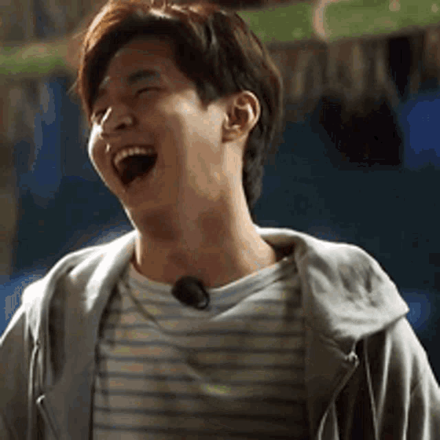 a man wearing a striped shirt and a gray jacket is laughing .