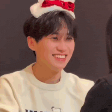 a young man wearing a santa hat is smiling and laughing .