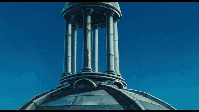a very tall building with columns and a blue sky in the background