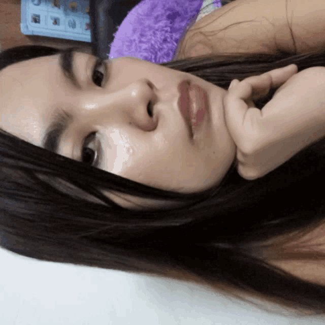 a woman is laying down with her hand on her chin