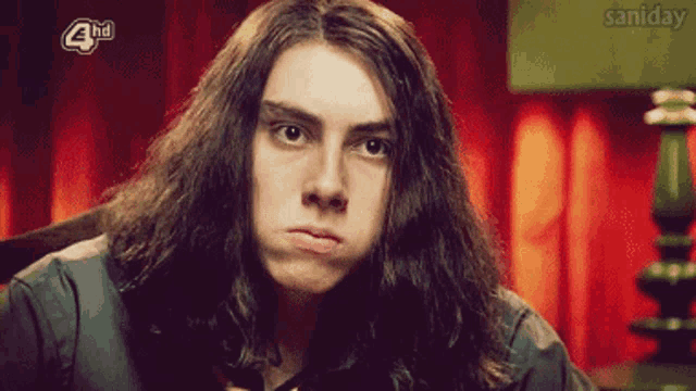 a young man with long hair is making a funny face in front of a screen that says 4 hd