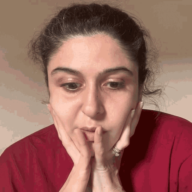 a woman with a ring on her finger holds her hands to her face