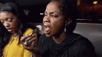 a woman is sticking her tongue out while another woman is holding a fork .