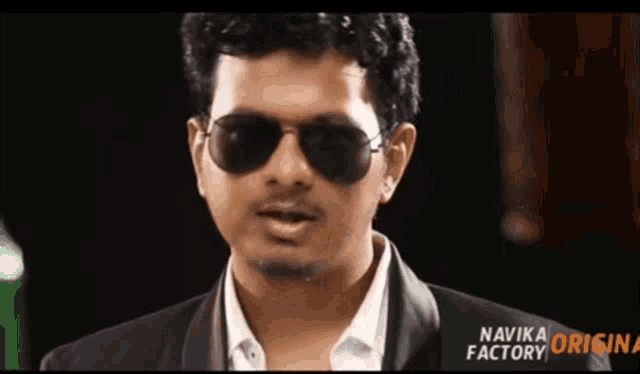 a man wearing sunglasses and a suit has the name navika factory on the bottom