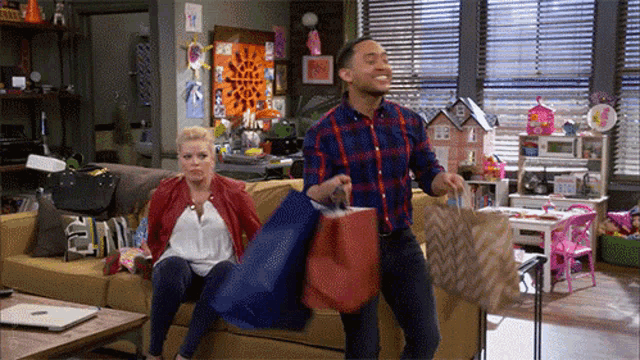 a man and woman sitting on a couch with shopping bags