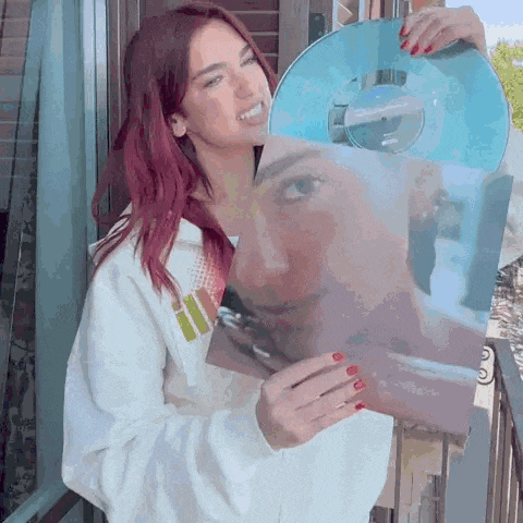 a woman with red hair is holding a blue record with a picture of her face on it