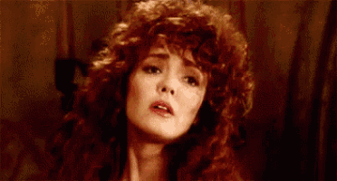 a close up of a woman with red curly hair making a funny face .