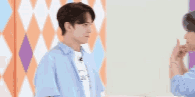 a young man in a blue shirt is making a funny face and pointing at something .