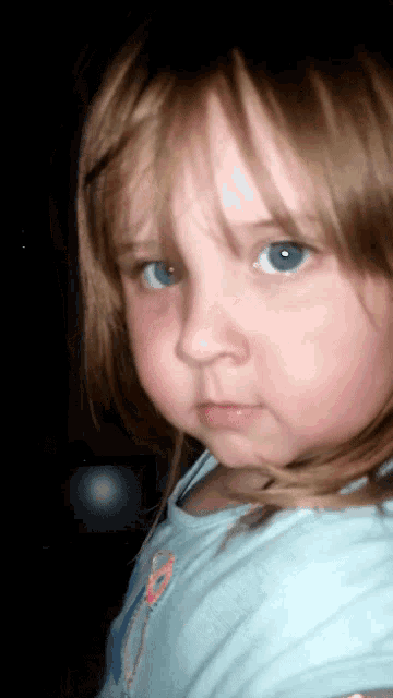 a close up of a little girl 's face with blue eyes