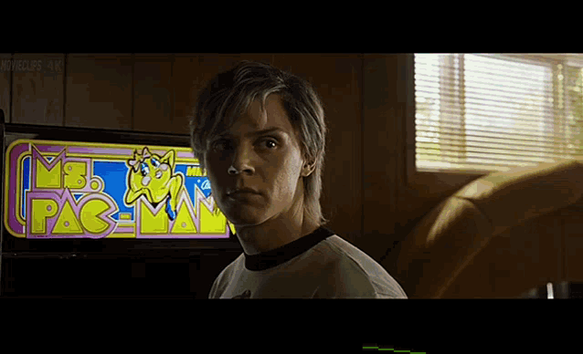 a man is standing in front of an arcade game that says pac man