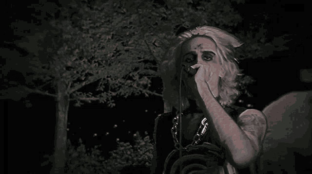 a man with a cross on his forehead is singing into a microphone and giving the middle finger