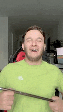 a man in a green t-shirt is holding a tablet and smiling .