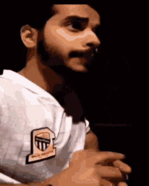 a man with a beard is wearing a white shirt and making a face .