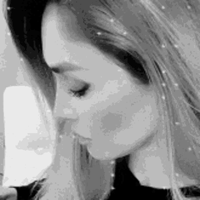 a black and white photo of a woman holding her finger to her mouth .
