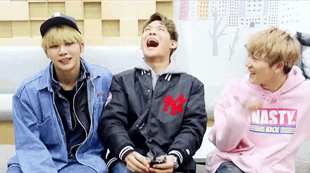 a group of young men are sitting on a couch laughing .