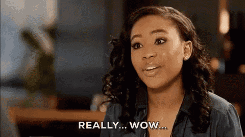 a woman is sitting at a table with her mouth open and says really wow .